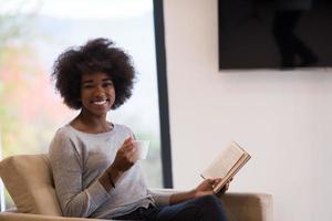 mujer negra leyendo un libro frente a la chimenea foto