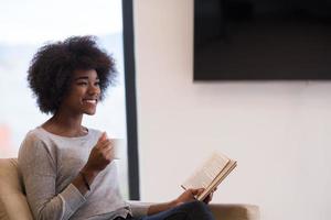 black woman reading book  in front of fireplace photo