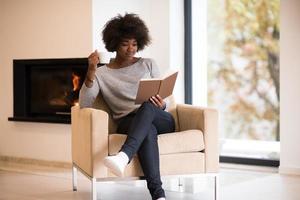 mujer negra leyendo un libro frente a la chimenea foto
