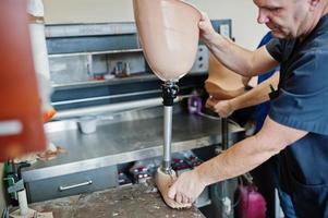 Two prosthetist man workers making prosthetic leg while working in laboratory. photo