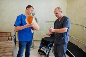Two prosthetist man workers with prosthetic leg working in laboratory. photo