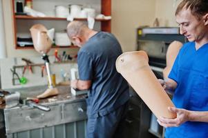 Two prosthetist man workers making prosthetic leg while working in laboratory. photo