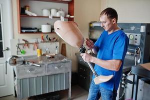 Prosthetist man making prosthetic leg while working in laboratory. photo