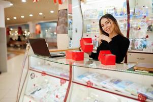 retrato de una joven vendedora caucásica sostiene cajas de regalo rojas. pequeña empresa de tienda de souvenirs de dulces. foto