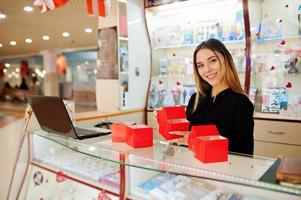 Portrait of young caucasian female woman seller hold red gift boxes. Small business of candy souvenirs shop. photo