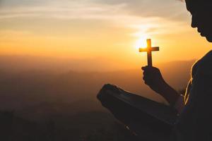 A women is praying to God on the mountain. Praying hands with faith in religion and belief in God on blessing background. Power of hope or love and devotion. photo