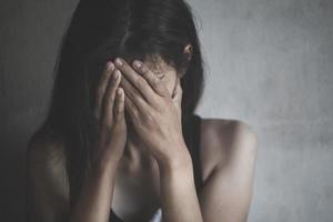A woman hiding face. Violence against women concept. Depressed teenager sitting holding head in hands, stressed sad young woman having mental problems. photo