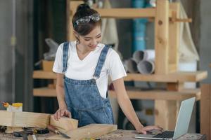 A carpenter woman works in her own woodworking shop. She uses a tablet while in her workspace. small business concept photo
