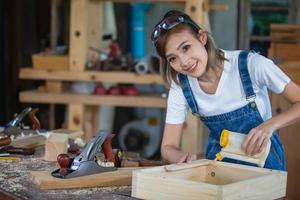 feliz y atractiva trabajadora carpintera profesional de mediana edad que busca y elige madera en el taller.