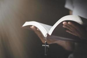 una mujer sostiene la biblia en sus manos y estudia la palabra de dios. buscando la verdad en las escrituras. orando por las bendiciones de dios. foto