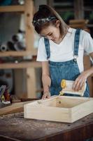 feliz y atractiva trabajadora carpintera profesional de mediana edad que busca y elige madera en el taller.