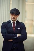 Portrait of retro 1920s english arabian business man wearing dark suit, tie and flat cap. photo