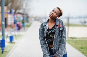 joven afroamericana milenaria en la ciudad. mujer negra feliz con auriculares inalámbricos. concepto de generación z. foto