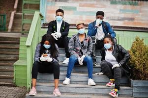 grupo de amigos adolescentes africanos en el parque que usan máscaras médicas protegen de infecciones y enfermedades cuarentena del virus del coronavirus. foto