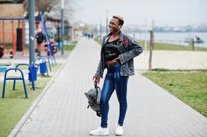 Young millennial african american girl in city. Happy black woman with wireless earphones. Generation Z concept. photo