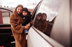 la joven madre y el niño se paran cerca de su auto todoterreno. concepto de conducción segura. foto