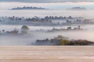 mesa de madera sobre niebla borrosa en el bosque - se puede utilizar para montar o exhibir sus productos foto