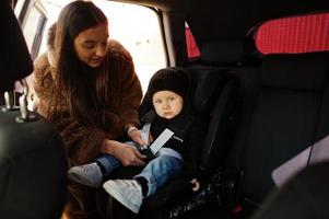 Young mother and child in car. Baby seat on chair. Safety driving concept. photo