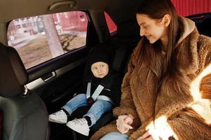 joven madre e hijo en coche. asiento de bebé en silla. concepto de conducción segura. foto