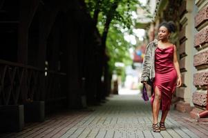 Portrait of a beautiful natural young African woman with afro hair. Black model in red silk dress. photo