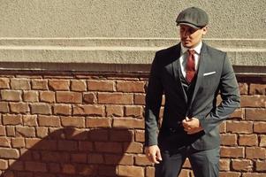 Portrait of retro 1920s english arabian business man wearing dark suit, tie and flat cap. photo