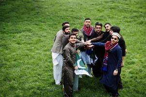 grupo de hombres paquistaníes vestidos con ropa tradicional salwar kameez o kurta con banderas de pakistán. foto