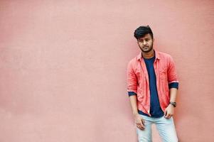 Portrait of young stylish indian man model isolated on pink wall background. photo