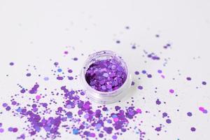 Glitter for nails and body.Beautiful glitter for nails and body close-up. Purple glitter on gray background photo