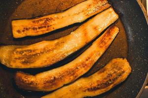 Close up eggplant slices fry in saucepan with oil in kitchen photo