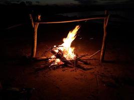 la hoguera arde por la noche en la orilla del lago foto
