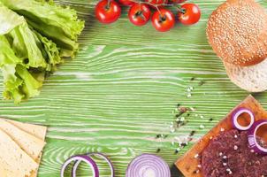 The ingredients for the burger on green wooden background photo