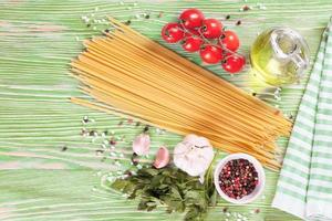 Pasta and cooking ingredients on green wooden background. photo