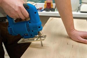 Image of a man hand using electric jigsaw photo