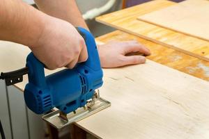 Image of a man hand using electric jigsaw photo