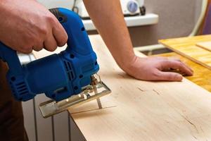 Image of a man hand using electric jigsaw photo