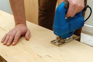 Image of a man hand using electric jigsaw photo