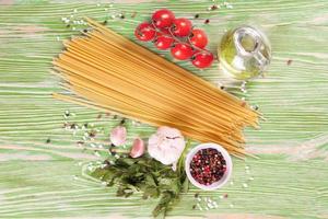 Pasta and cooking ingredients on green wooden background. photo