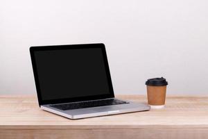 Front view of the laptop and take-out coffee  is on the work table concrete background photo