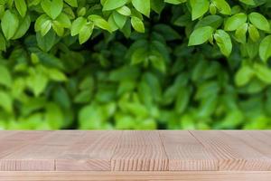 mesa de madera marrón sobre fondo de naturaleza verde abstracto bokeh - se puede utilizar para montar o mostrar sus productos foto