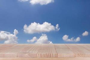 mesa de madera marrón sobre fondo de cielo azul abstracto bokeh - se puede utilizar para montar o mostrar sus productos foto