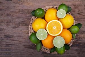 Mix of fresh citrus fruits in basket on wood photo