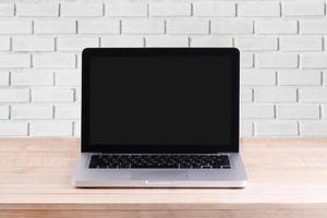 Front view of the laptop is on the work table brick background photo