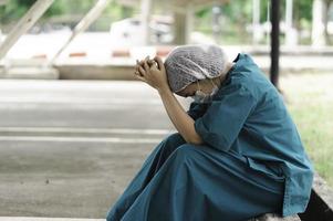 Tired depressed female asian scrub nurse wears face mask blue uniform sits on hospital floor,Young woman doctor stressed from hard work photo