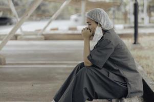 Tired depressed female asian scrub nurse wears face mask blue uniform sits on hospital floor,Young woman doctor stressed from hard work photo