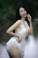 retrato de mujer asiática sexy en la cascada, sintiéndose fresca en el río, mujer tailandesa relajada en el campo foto