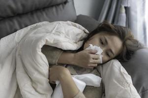 Asian sick woman sit on the sofa stay at home,The woman felt bad, wanted to lie down and rest,high fever photo