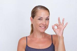 mujer mostrando ok como signo con los dedos sobre fondo blanco foto