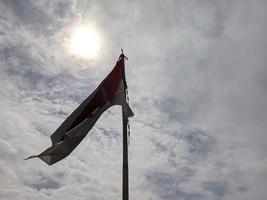 ondeando la bandera indonesia con postes de bambú y la belleza del sol sobre ella foto