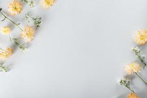 chrysanthemum and cutter flowers composition. Pattern and Frame made of various yellow or orange flowers and green leaves on white background. Flat lay, top view, copy space, spring, summer concept. photo