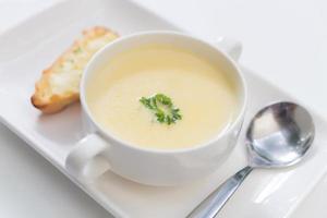 Delicious corn soup In a white bowl served with bread. photo